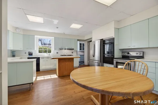 a living room with stainless steel appliances furniture a fireplace and a rug