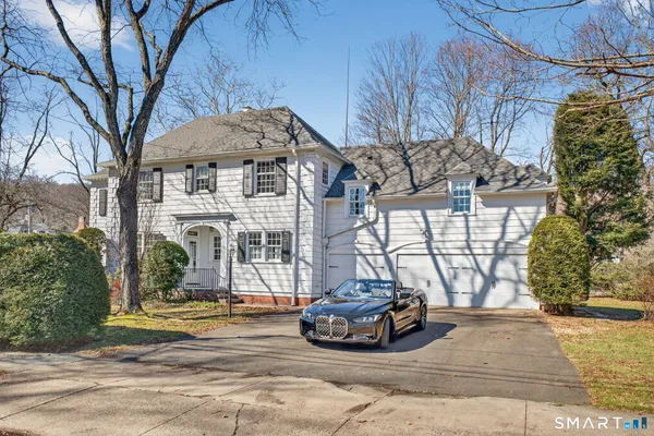 a view of a white house with large tree and wooden fence
