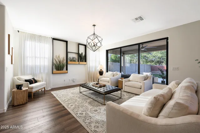 a view of a dining room and livingroom with furniture wooden floor a rug a chandelier
