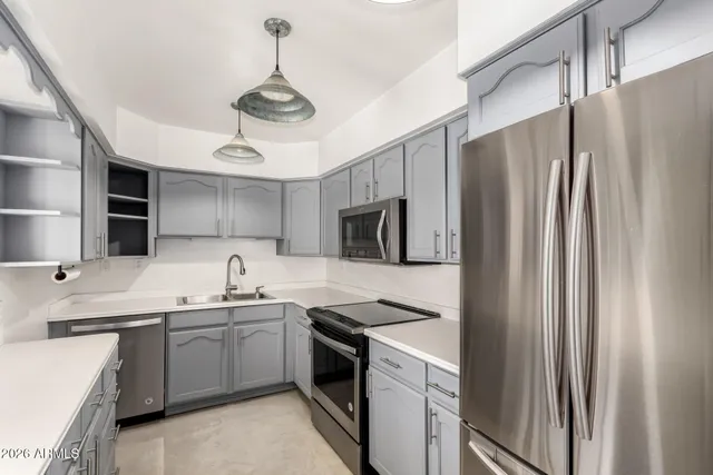 a kitchen with stainless steel appliances a sink a stove a refrigerator cabinets and a window