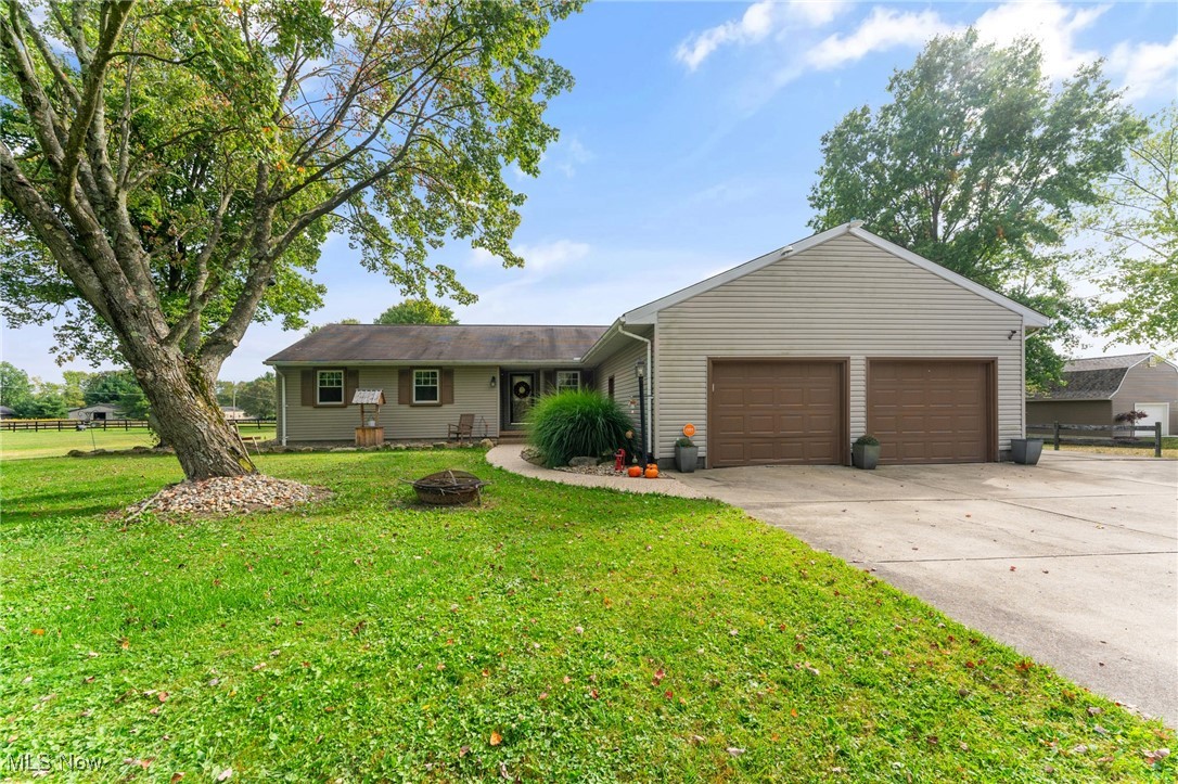 Ranch-style house with a fire pit, a front yard, and a garage