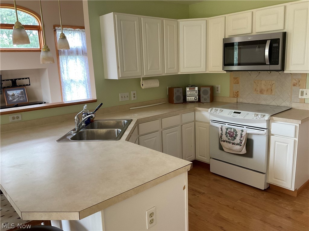 8603 Murray Road Cleveland, OH 44125 - Photo 2 of 26 Kitchen with decorative light fixtures, white electric stove, sink, light wood-type flooring, and tasteful backsplash