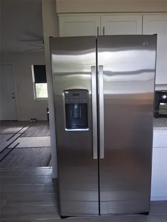 a view of a refrigerator in kitchen and an empty room