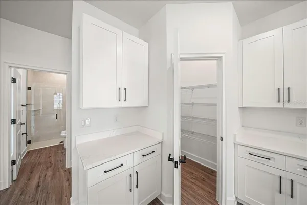 an empty room with wooden floor closet and windows