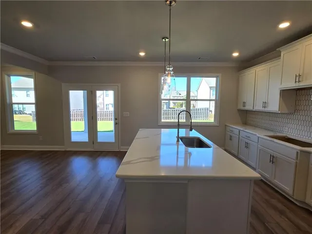 a kitchen with kitchen island granite countertop a sink a window and wooden floor