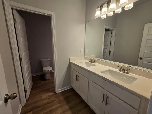 a bathroom with a double vanity sink a toilet and a mirror