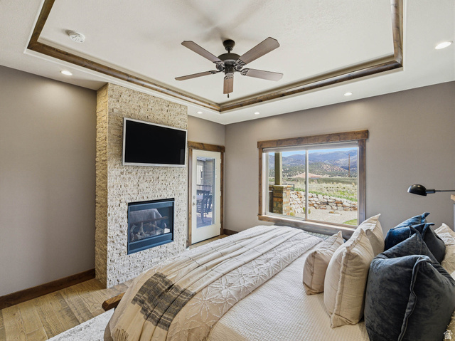 402 Shadow Hill Road Wanship, UT 84017 - Photo 23 of 90 Bedroom with hardwood / wood-style floors, a tray ceiling, ceiling fan, a fireplace, and recessed lighting