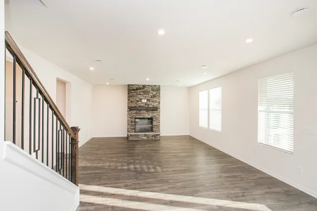 a view of an empty room with wooden floor and stairs