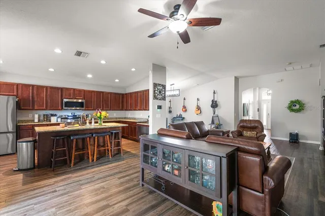 a kitchen with stainless steel appliances granite countertop a stove refrigerator and a dining table with wooden floor