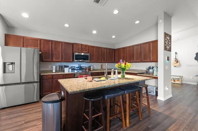 a kitchen with wooden cabinets refrigerator and chairs