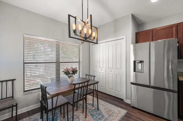 a kitchen with stainless steel appliances granite countertop a dining table chairs and refrigerator