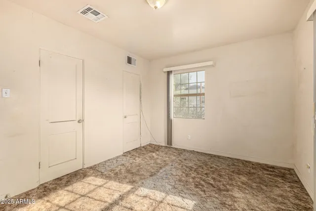 a view of an empty room with window and closet area