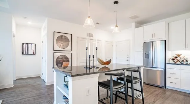 a kitchen with stainless steel appliances granite countertop a sink a stove a refrigerator and cabinets with wooden floor