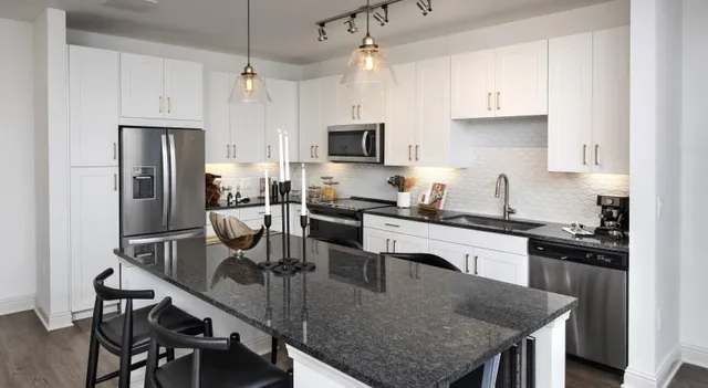 a kitchen with granite countertop kitchen island stainless steel appliances a sink stove and refrigerator