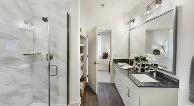 a bathroom with a granite countertop sink a mirror and shower