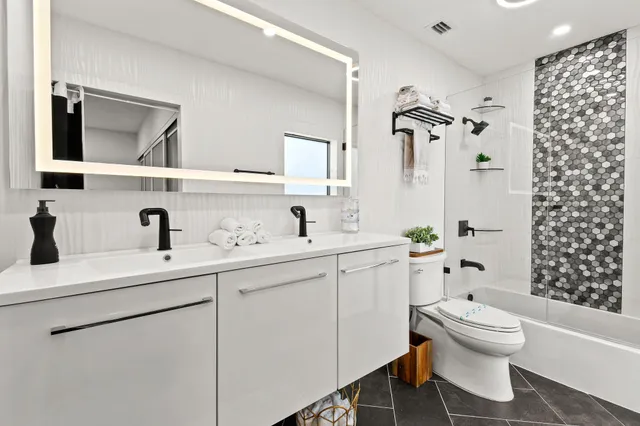 a bathroom with a toilet sink double vanity and mirror