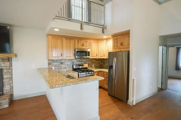 a kitchen with stainless steel appliances granite countertop a refrigerator a stove and a sink