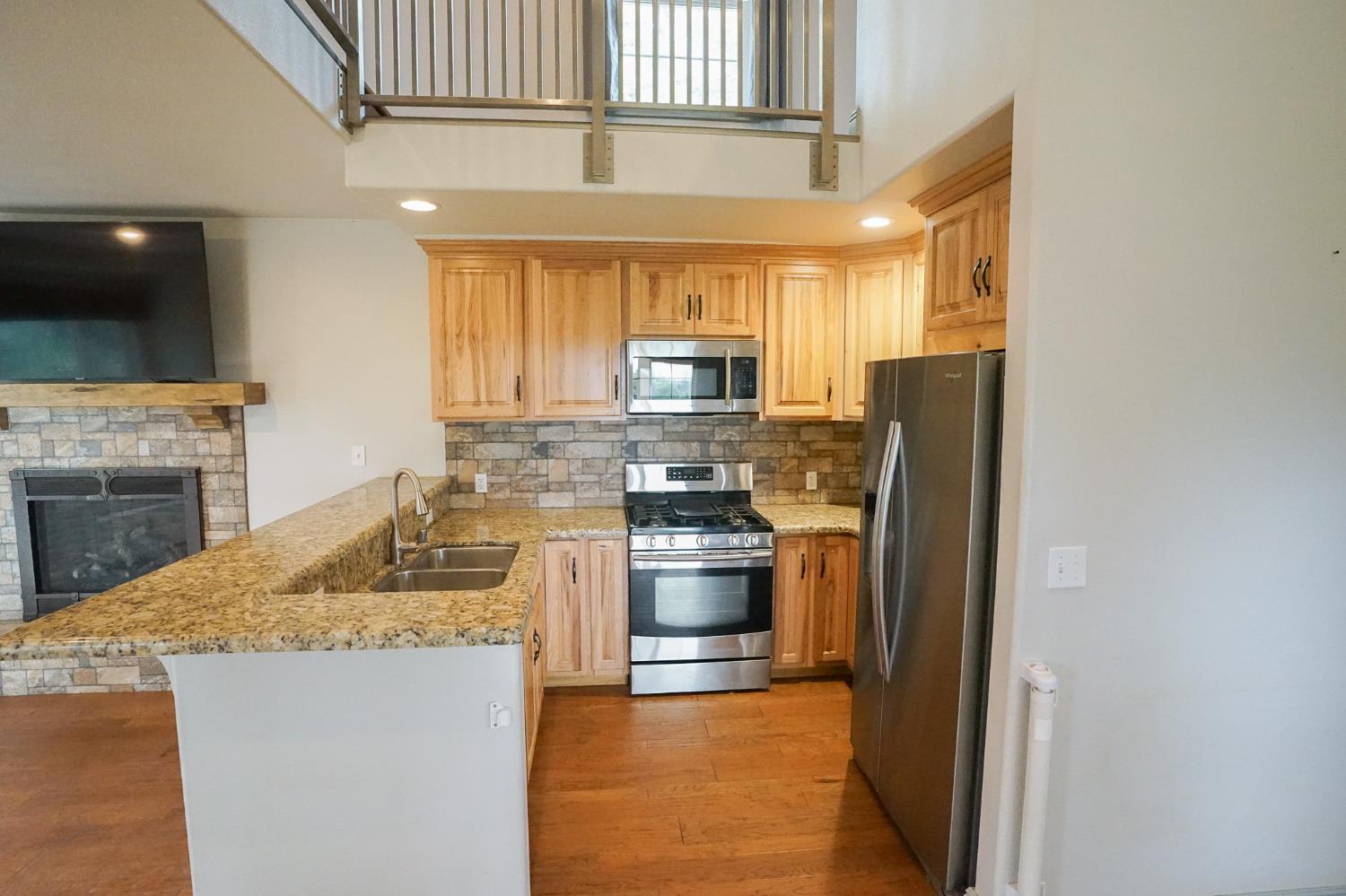 16375 Jesus Maria Road Mokelumne Hill, CA 95245 - Photo 13 of 39 a kitchen with stainless steel appliances granite countertop a refrigerator a stove and a sink with wooden floor