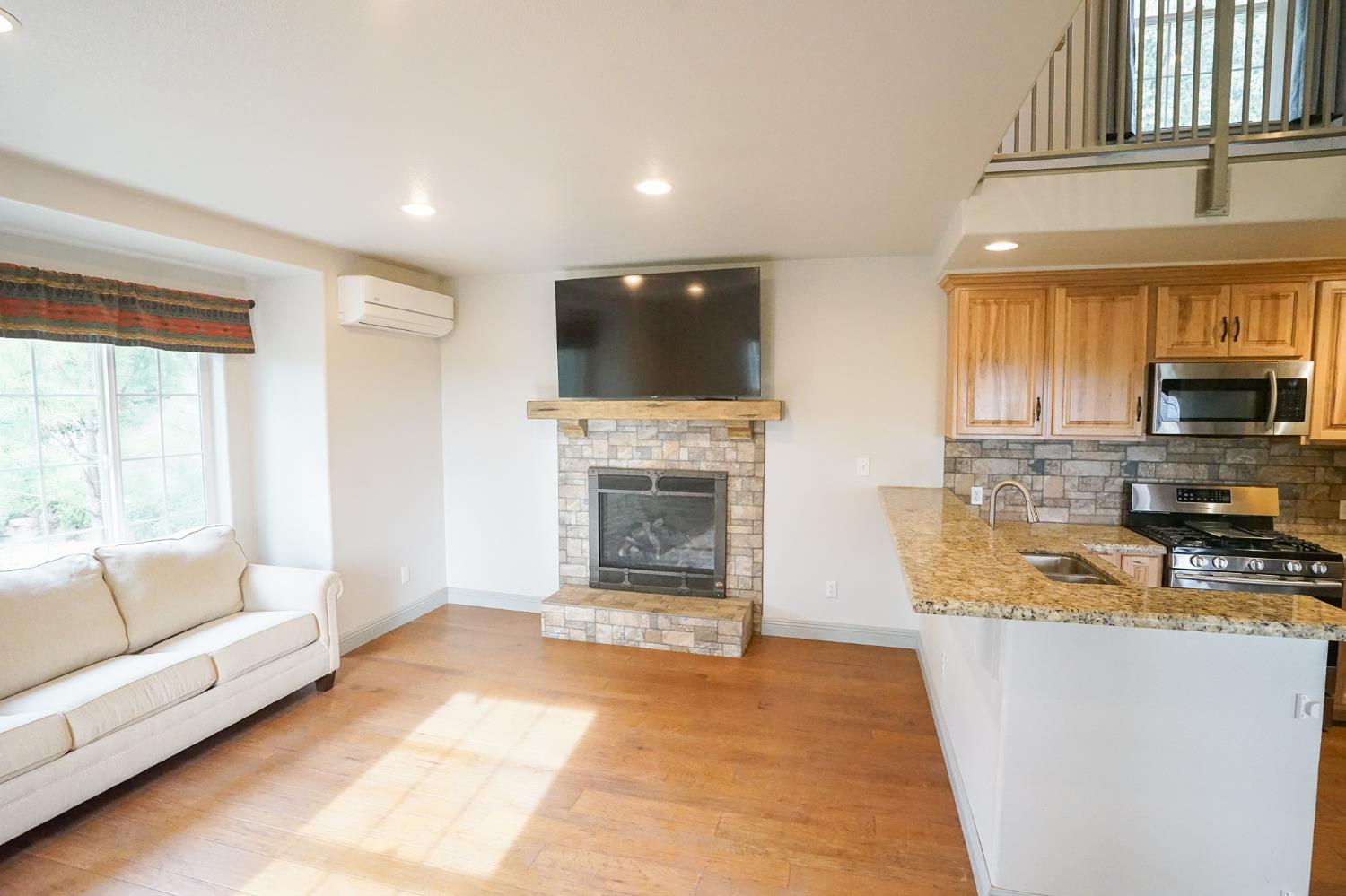 16375 Jesus Maria Road Mokelumne Hill, CA 95245 - Photo 9 of 39 a living room with stainless steel appliances granite countertop furniture a fireplace a flat screen tv and a large window