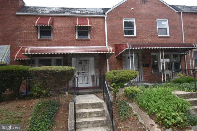 a view of a house with brick walls and a yard with plants