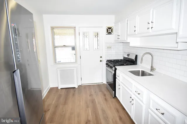a kitchen with granite countertop a refrigerator sink and white cabinets