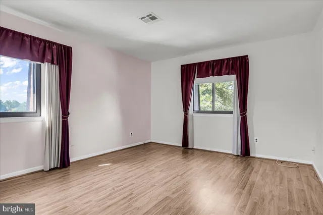 an empty room with wooden floor and windows