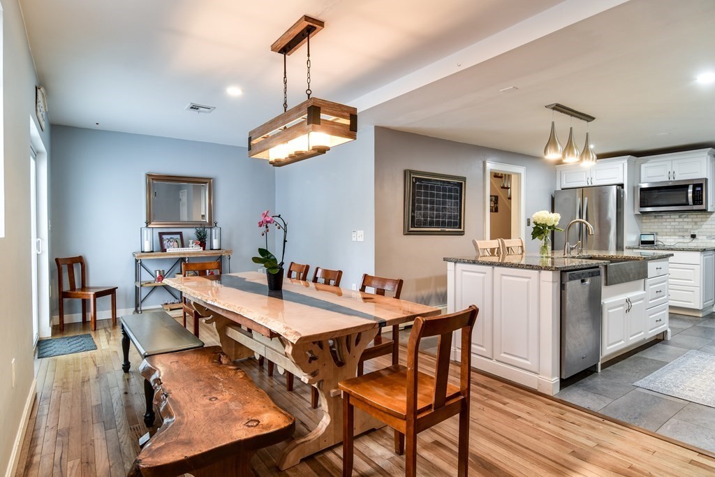 514 Edgell Road Framingham, MA 01701 - Photo 8 of 35 a dining room with stainless steel appliances kitchen island granite countertop a table chairs and a refrigerator
