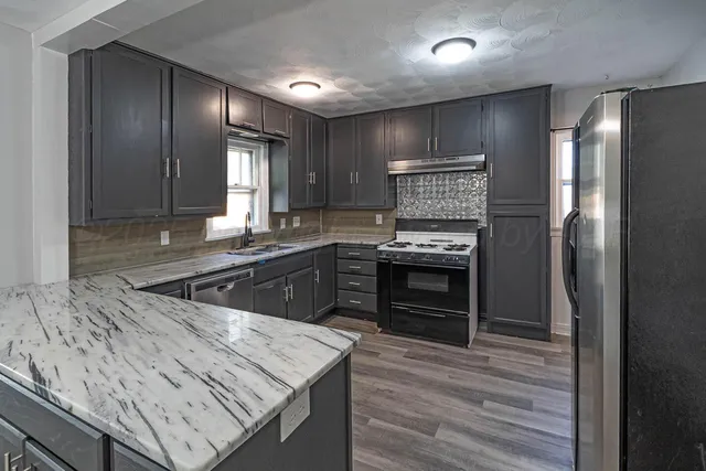 a kitchen with stainless steel appliances granite countertop wooden cabinets a refrigerator and a stove