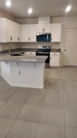 a kitchen with stainless steel appliances granite countertop a stove a sink and a microwave