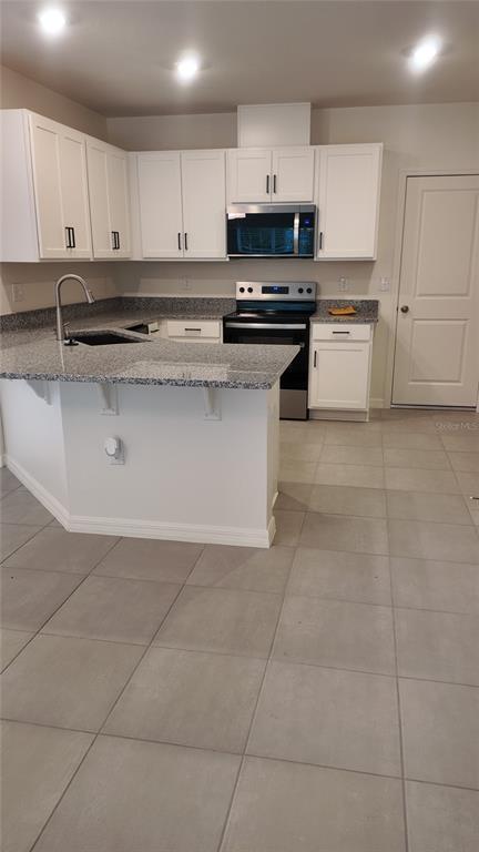 2798 Raindrop Run Street Clermont, FL 34714 - Photo 8 of 18 a kitchen with stainless steel appliances granite countertop a stove a sink and a microwave