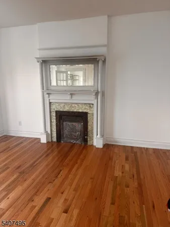 a view of empty room with wooden floor and fireplace