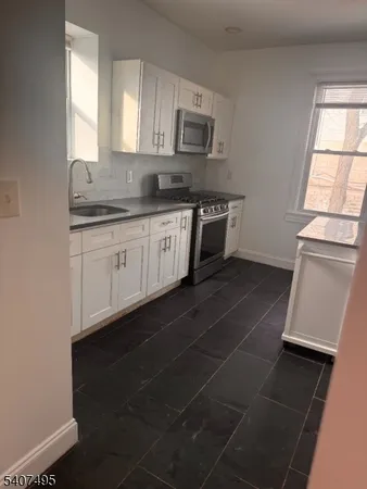 a kitchen with stainless steel appliances a sink dishwasher a stove a microwave and a window