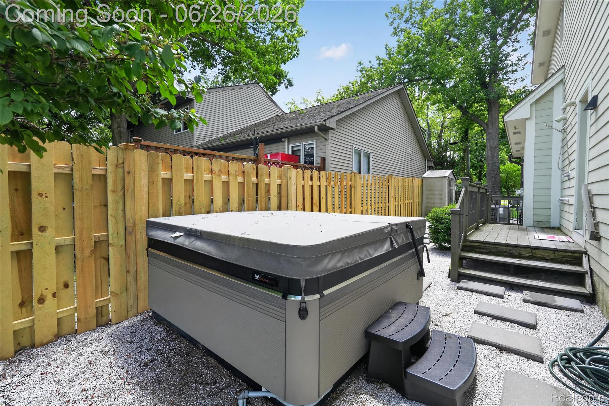 3478 Lexington Road Waterford, MI 48328 - Photo 34 of 52 Private outdoor spa area featuring a hot tub with cover, gravel ground cover, a new wood privacy fence, and stepping stones leading to a wooden deck with stairs
