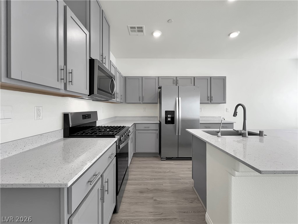 9984 Indigo Cliffs Street Las Vegas, NV 89141 - Photo 7 of 31 Kitchen featuring a sink, gray cabinetry, visible vents, and stainless steel appliances