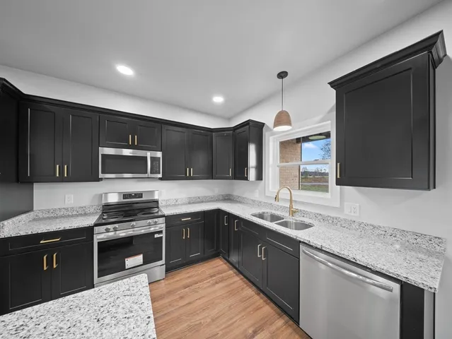 a kitchen with stainless steel appliances granite countertop a sink stove microwave and refrigerator