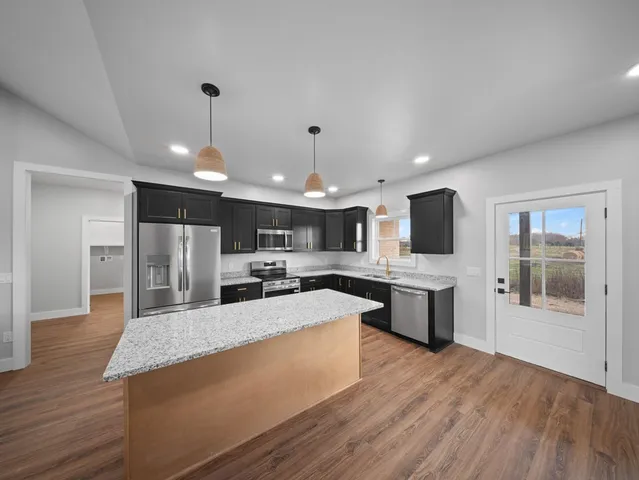 a large kitchen with kitchen island a large counter space a sink appliances and cabinets