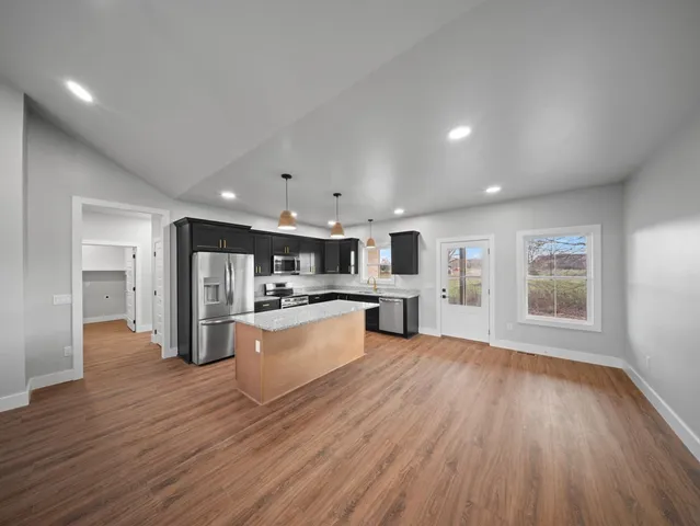 a view of kitchen with microwave a refrigerator and wooden floor