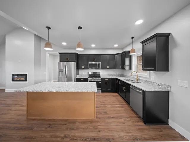 a large kitchen with kitchen island a sink wooden floor and stainless steel appliances
