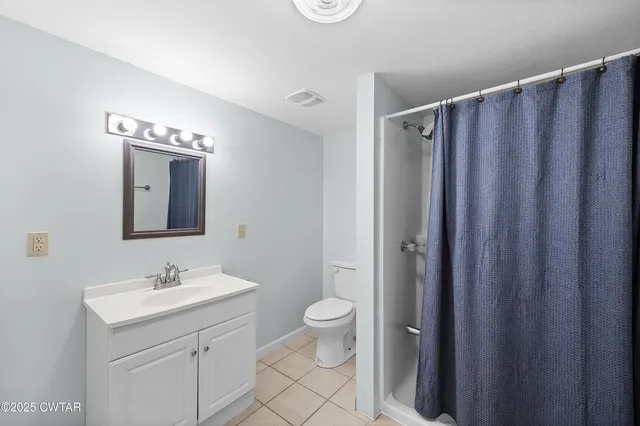 a bathroom with a granite countertop sink toilet and mirror