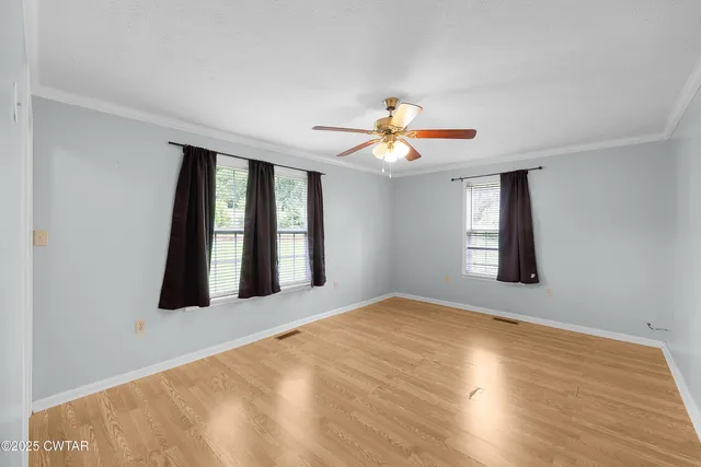 a view of an empty room with window and chandelier fan