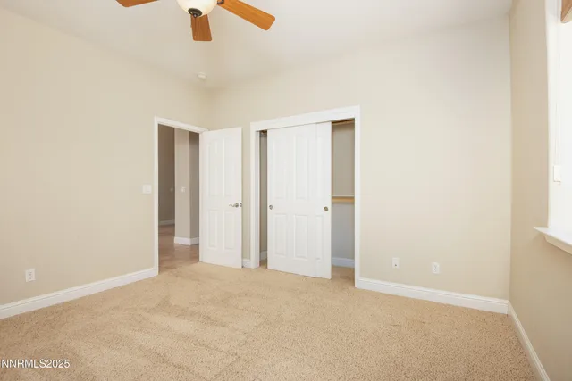 an empty room with ceiling fan and window