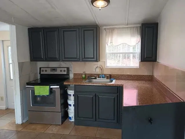 a kitchen with kitchen island a stove a sink and a window
