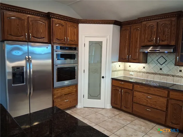 a kitchen with stainless steel appliances granite countertop a refrigerator and a sink