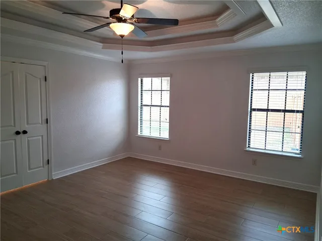 a view of an empty room with window and wooden floor