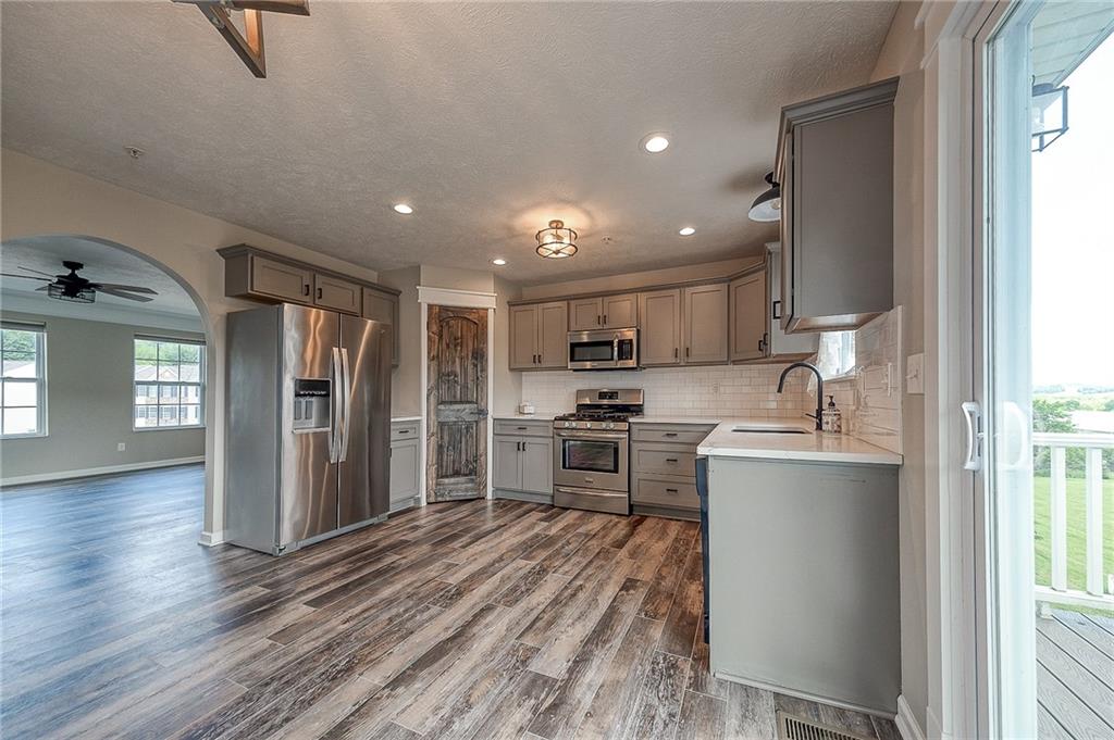 131 Rylie Drive Harmony, PA 16037 - Photo 6 of 34 a kitchen with stainless steel appliances kitchen island granite countertop a refrigerator a sink dishwasher a stove and a dining table with wooden floor