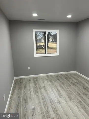 an empty room with wooden floor and window
