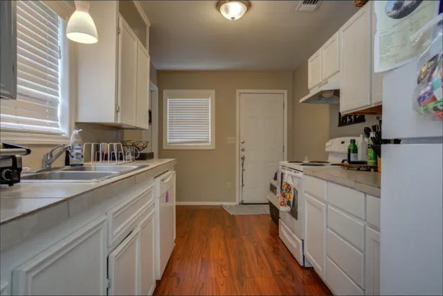 a kitchen with a sink a stove cabinets and wooden floor