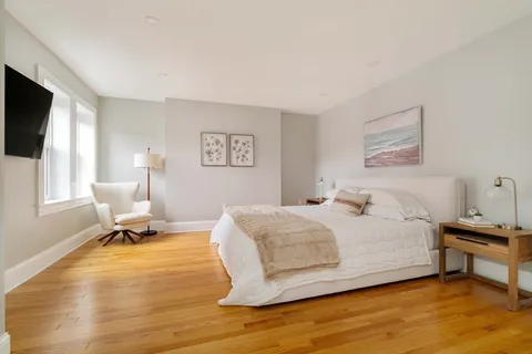 a bedroom with a bed a chair and a flat screen tv