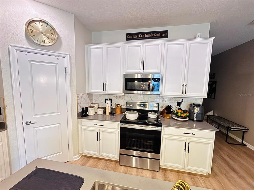 279 Bergamot Loop Davenport, FL 33837 - Photo 8 of 38 a kitchen with white cabinets stainless steel appliances and wooden floor