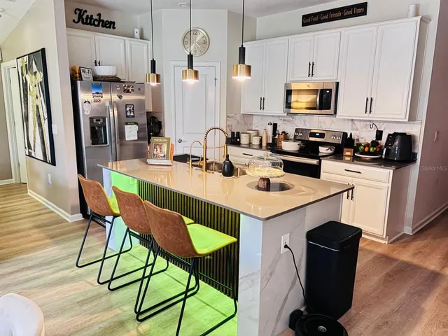 a kitchen with stainless steel appliances kitchen island granite countertop a table chairs microwave and sink